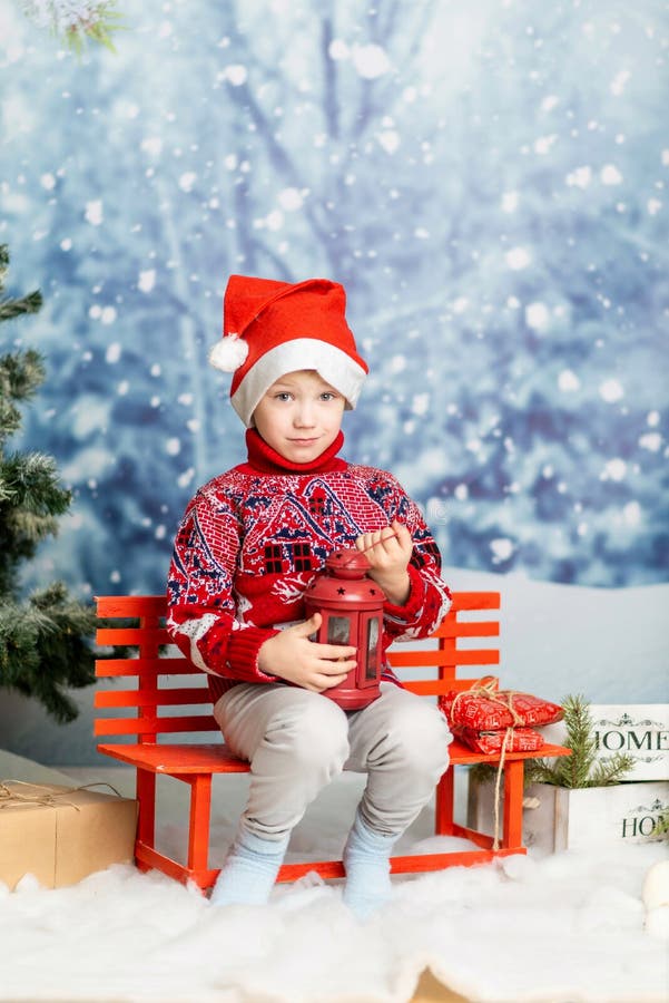 Un băiețel într-o pălărie de Crăciun și un pulover roșu cu un felinar stock images