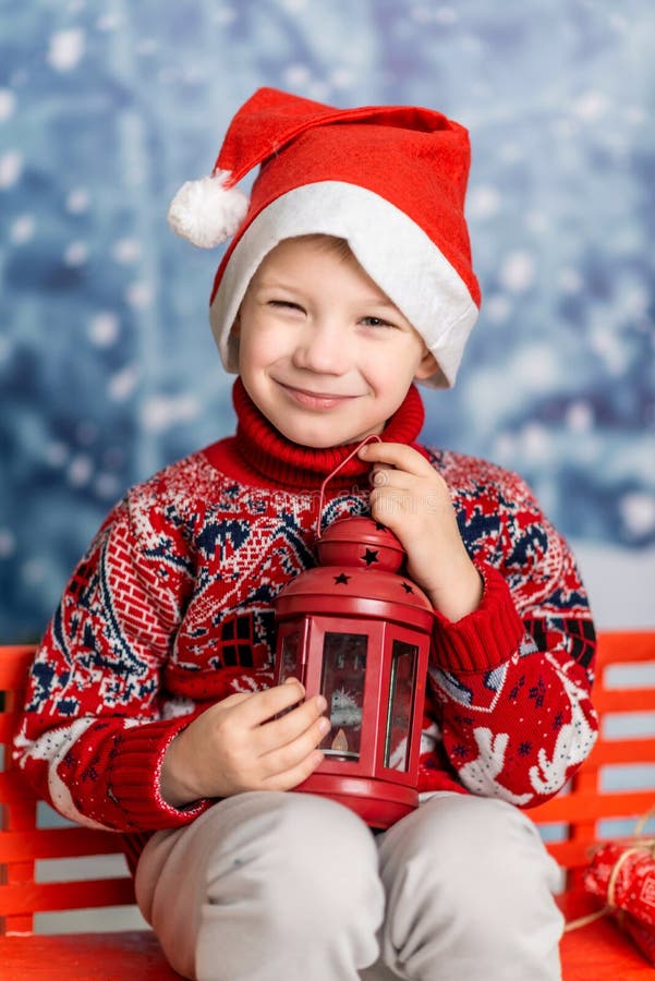 Un băiețel într-o pălărie de Crăciun și un pulover roșu cu un felinar royalty free stock image