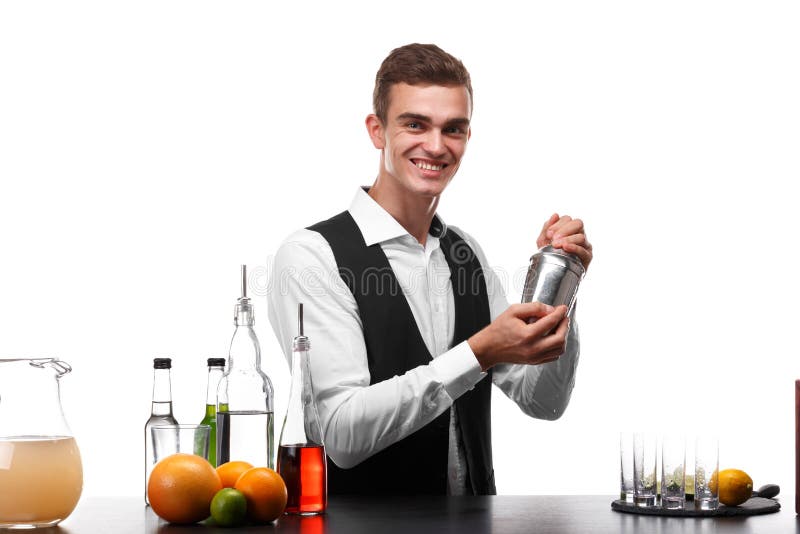 Un camarero atractivo con una coctelera en un contador de la barra, cal, naranjas, limones en un fondo blanco fotografía de archivo libre de regalías Un camarero atractivo con una coctelera en un contador de la barra, cal, naranjas, limones en un fondo blanco fotografía de archivo libre de regalías
