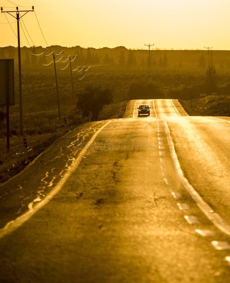 A yellow road at dusk with an aproaching car. A yellow road at dusk with an aproaching car