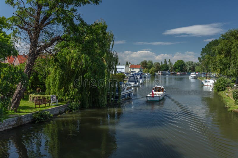 Un canot automobile croise vers Beccles Quay sur la rivière Waveney photo libre de droits Un canot automobile croise vers Beccles Quay sur la rivière Waveney photo libre de droits