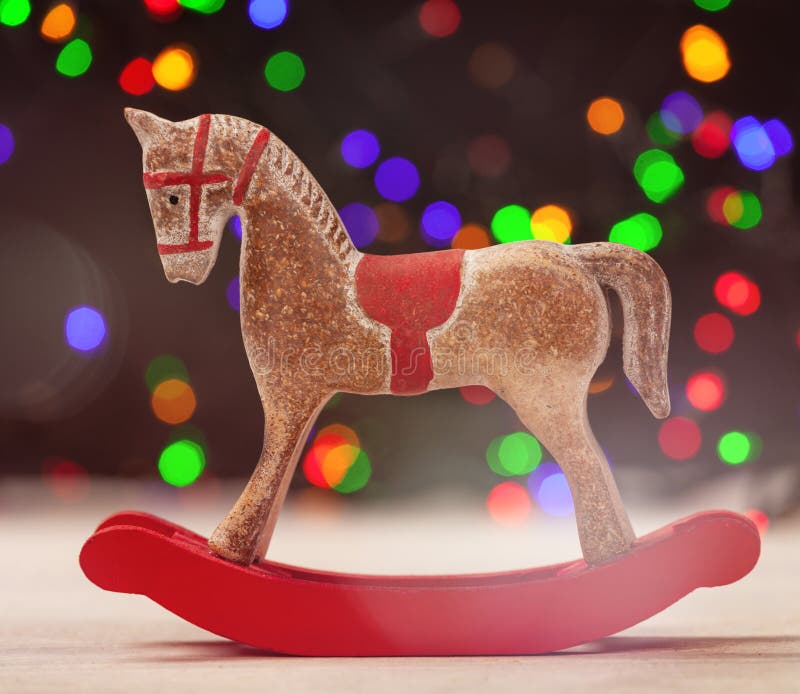 Un cavallo a dondolo con le luci di natale su fondo immagine stock Un cavallo a dondolo con le luci di natale su fondo immagine stock