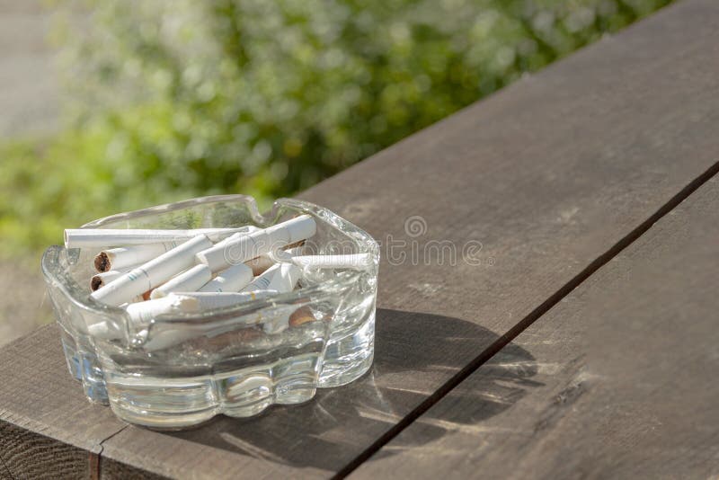 An ashtray with cigarettes is on the table. An ashtray with cigarettes is on the table.
