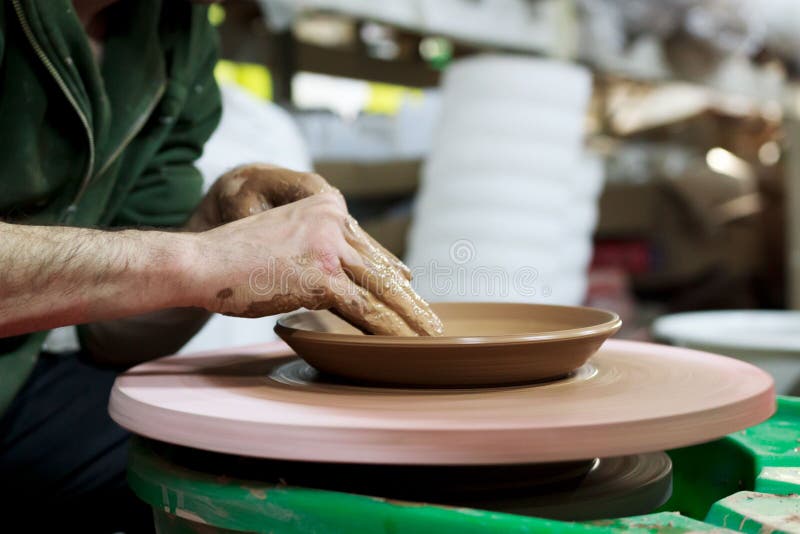Un ceramist principal avec 13 ans d'expérience fait le plat à partir de l'argile rouge sur une roue de potier, sur une feuille de images libres de droits Un ceramist principal avec 13 ans d'expérience fait le plat à partir de l'argile rouge sur une roue de potier, sur une feuille de images libres de droits