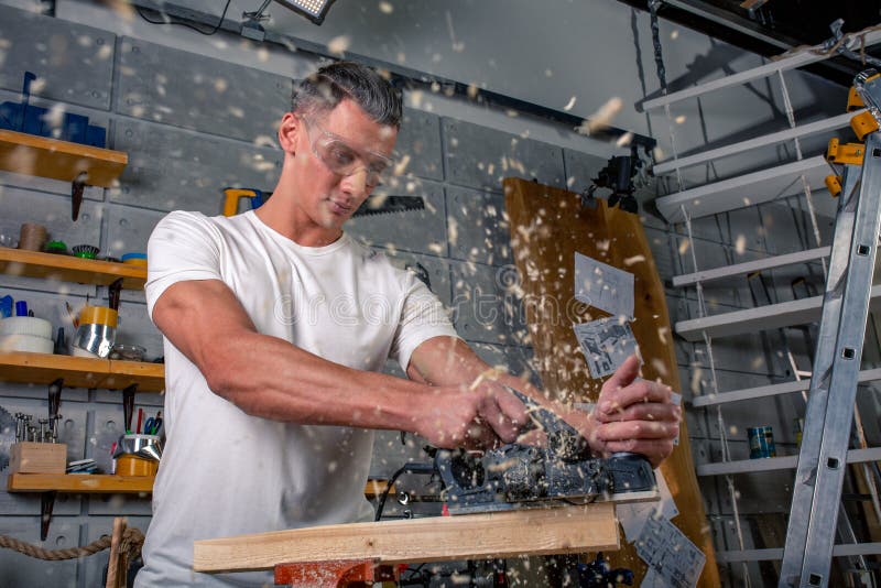 Un charpentier travaille au travail du bois la machine-outil Scie des détails de meubles avec une scie circulaire Processus de sc photographie stock libre de droits Un charpentier travaille au travail du bois la machine-outil Scie des détails de meubles avec une scie circulaire Processus de sc photographie stock libre de droits