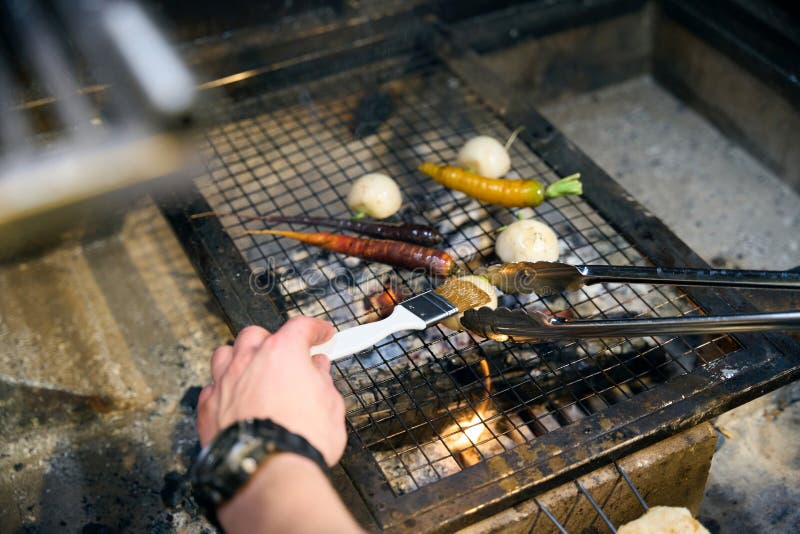 Un chef varón parcial frotando cebolla y friendo verduras en un lugar de incendio fotografía de archivo libre de regalías
