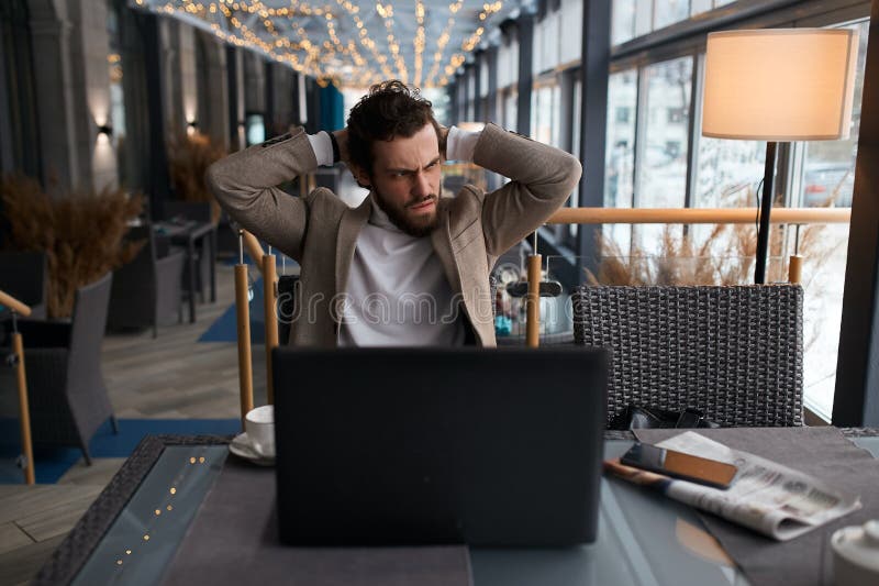 Un chico decepcionado y estresado tiene mala conexión wifi en el café foto de archivo libre de regalías