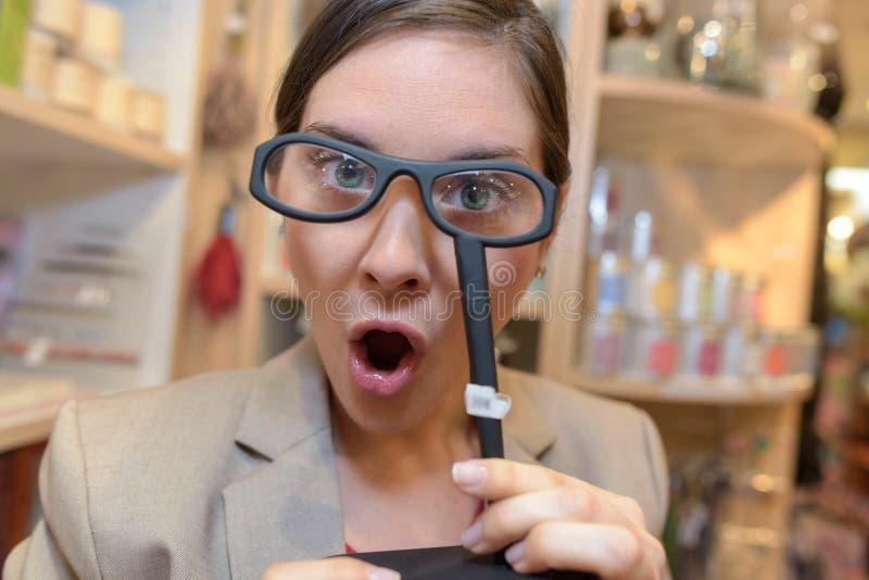Un cliente femminile che cerca di ingrandire gli occhiali al negozio fotografia stock libera da diritti Un cliente femminile che cerca di ingrandire gli occhiali al negozio fotografia stock libera da diritti