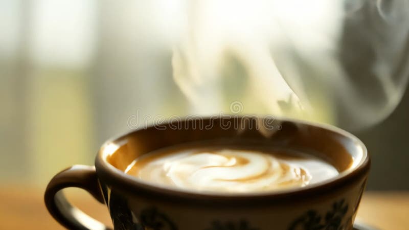 Un closeup d'un café chaud à vapeur avec une mousse de lait très tourbillonnante dans une tasse décorative 4k Vidéo illustration stock