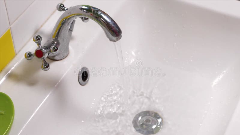 Un closeup d'un moyen branchant à la main l'évier ouvrant l'eau froide et remplissant l'évier. il ferme ensuite banque de vidéos