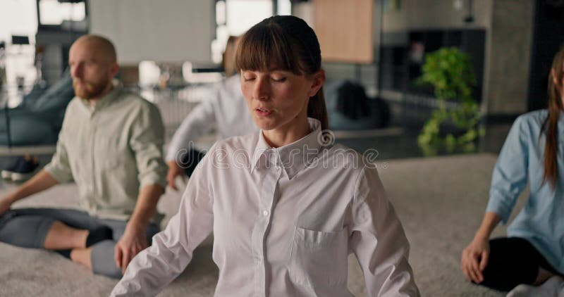 Un closeup d'une employée de bureau caucasienne qui guide ses collègues à travers des exercices d'étirement relaxant sur un tapis banque de vidéos