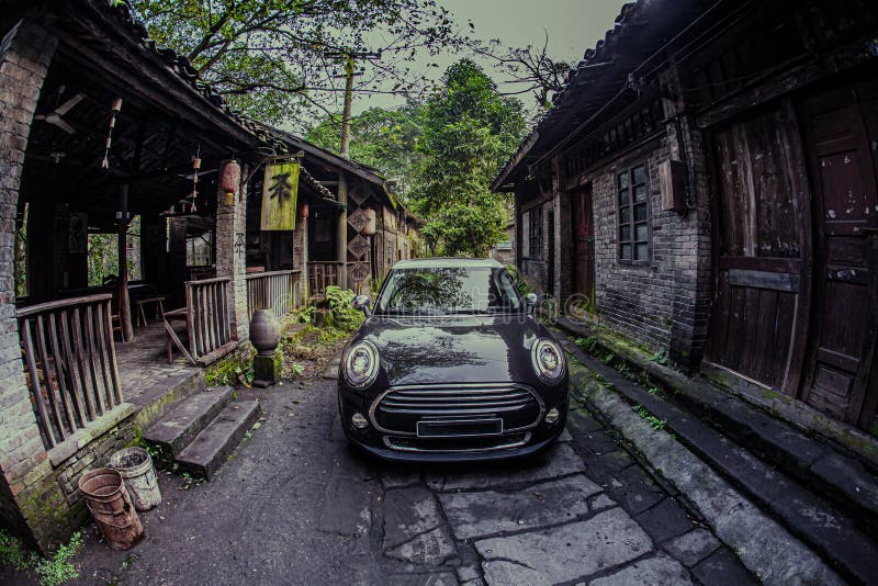 At night, a small black car is driving on a stone road in an ancient Chinese town. At night, a small black car is driving on a stone road in an ancient Chinese town