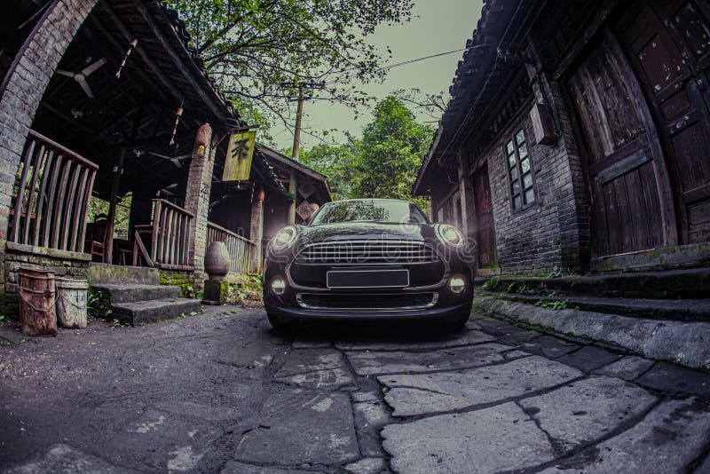 At night, a small black car is driving on a stone road in an ancient Chinese town. At night, a small black car is driving on a stone road in an ancient Chinese town