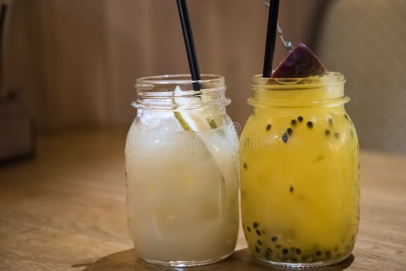 Un cocktail di frutti a passione e di pere un paio di lattine di limonata sono sul tavolo fotografia stock libera da diritti Un cocktail di frutti a passione e di pere un paio di lattine di limonata sono sul tavolo fotografia stock libera da diritti