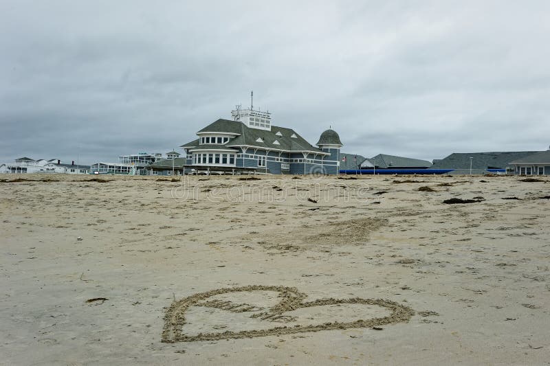 2023 Hampton Beach, New Hampshire. A large heart is drawn in the sand with the message Help written inside it with the Seashell stage building in the background. 2023 Hampton Beach, New Hampshire. A large heart is drawn in the sand with the message Help written inside it with the Seashell stage building in the background