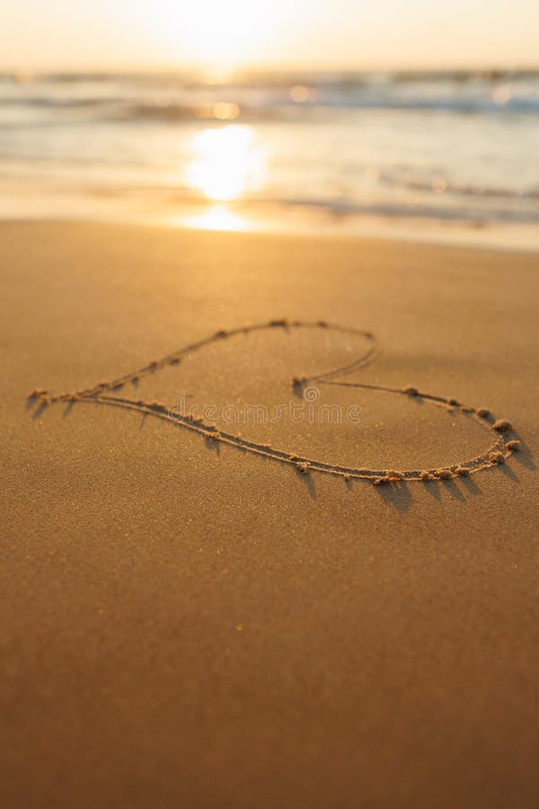 A heart is drawn on the sand on the beach at sunset. Romantic sunset on the beach. Heart shape. Heart symbol. Love. A heart is drawn on the sand on the beach at sunset. Romantic sunset on the beach. Heart shape. Heart symbol. Love