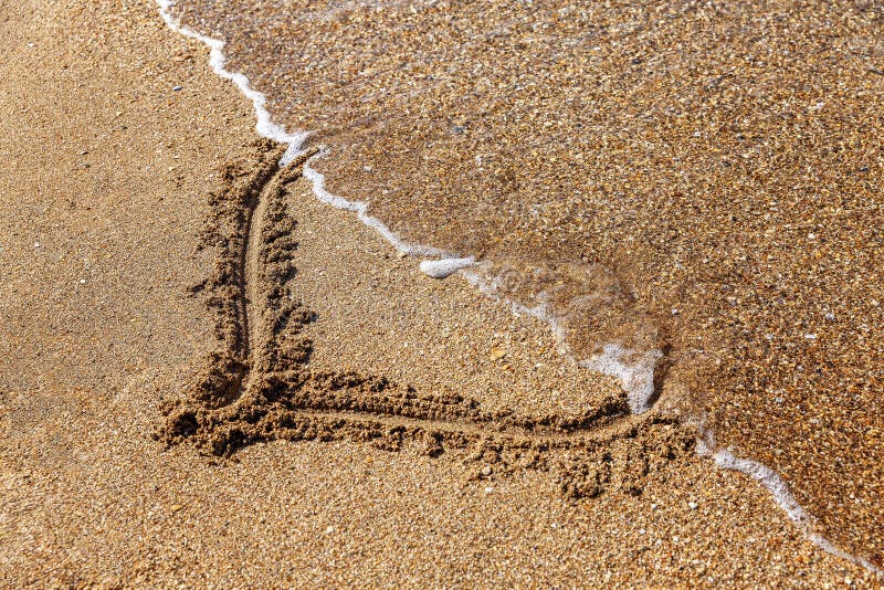 A heart drawn on the sand, half washed away by the wave. Love and relationship problems. Close-up. A heart drawn on the sand, half washed away by the wave. Love and relationship problems. Close-up.