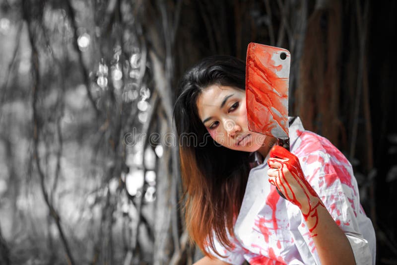 Un coltello della tenuta della donna con sangue nel parco, concetto di Halloween fotografia stock libera da diritti Un coltello della tenuta della donna con sangue nel parco, concetto di Halloween fotografia stock libera da diritti