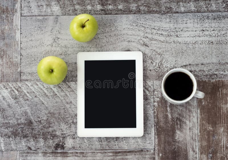 Un comprim? blanc avec une tasse de caf? et de pommes vertes se trouve sur la table images libres de droits Un comprim? blanc avec une tasse de caf? et de pommes vertes se trouve sur la table images libres de droits