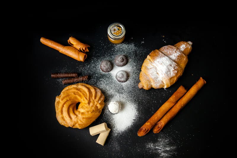 Un conjunto de dulces : trufa croissant eclair chocolate blanco sobre un fondo oscuro. concepto del día internacional de los dulce foto de archivo libre de regalías