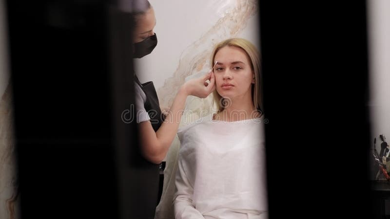 Un cosmetologo pulisce le sopracciglia con tamponi di cotone dopo un trucco permanente. video d archivio