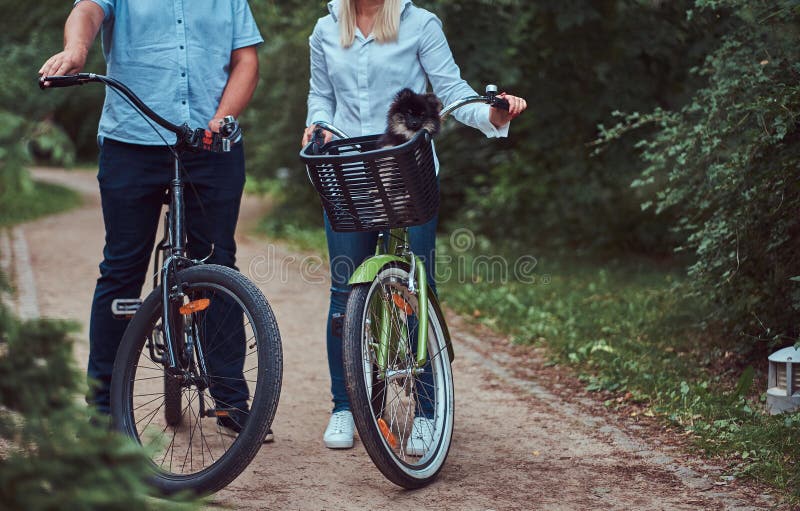 Un couple attrayant d'une femelle et d'un homme blonds s'est habillé dans des vêtements sport sur un tour de bicyclette avec leur photos stock Un couple attrayant d'une femelle et d'un homme blonds s'est habillé dans des vêtements sport sur un tour de bicyclette avec leur photos stock