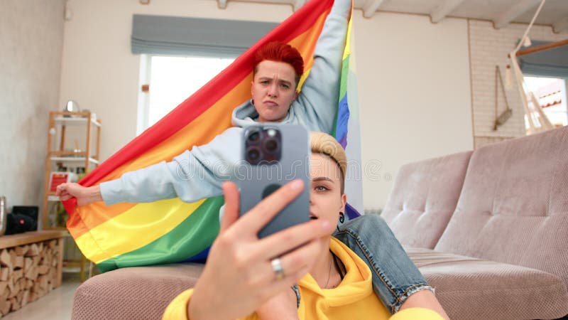 Un couple commémore la fierté en capturant un selfie avec un drapeau arc-en-ciel dans le confort de sa maison clips vidéos