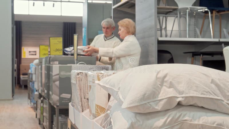 Un couple d'aînés explorant des oreillers confortables dans un magasin de mobilier élégant banque de vidéos