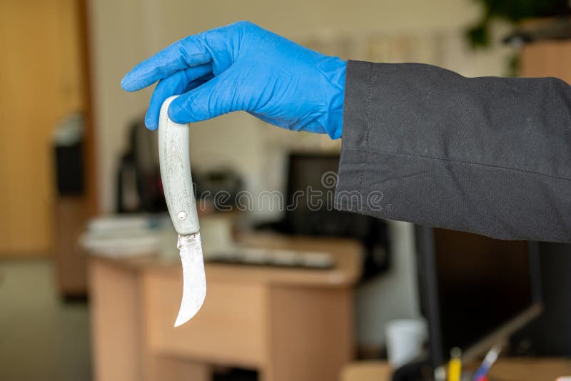 Un couteau avec une lame incurvée dans les mains d'un policier médico-légal avec des gants bleus en caoutchouc photos libres de droits Un couteau avec une lame incurvée dans les mains d'un policier médico-légal avec des gants bleus en caoutchouc photos libres de droits