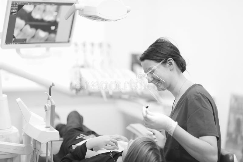 Un dentista de sexo femenino examina la cavidad bucal de un paciente fotos de archivo Un dentista de sexo femenino examina la cavidad bucal de un paciente fotos de archivo