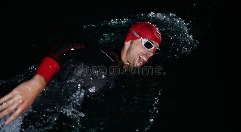 Un determinado triatleta profesional se somete a una rigurosa formación nocturna en aguas frías que exhibe dedicación y fotografía de archivo libre de regalías
