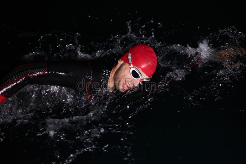 Un determinado triatleta profesional se somete a una rigurosa formación nocturna en aguas frías que exhibe dedicación y fotografía de archivo libre de regalías