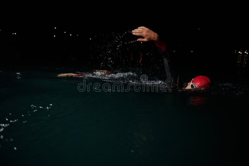 Un determinado triatleta profesional se somete a una rigurosa formación nocturna en aguas frías que exhibe dedicación y fotografía de archivo libre de regalías