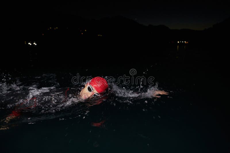 Un determinado triatleta profesional se somete a una rigurosa formación nocturna en aguas frías que exhibe dedicación y fotografía de archivo libre de regalías