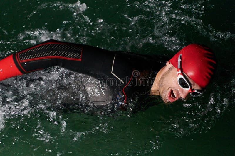 Un determinado triatleta profesional se somete a una rigurosa formación nocturna en aguas frías que exhibe dedicación y imagen de archivo libre de regalías
