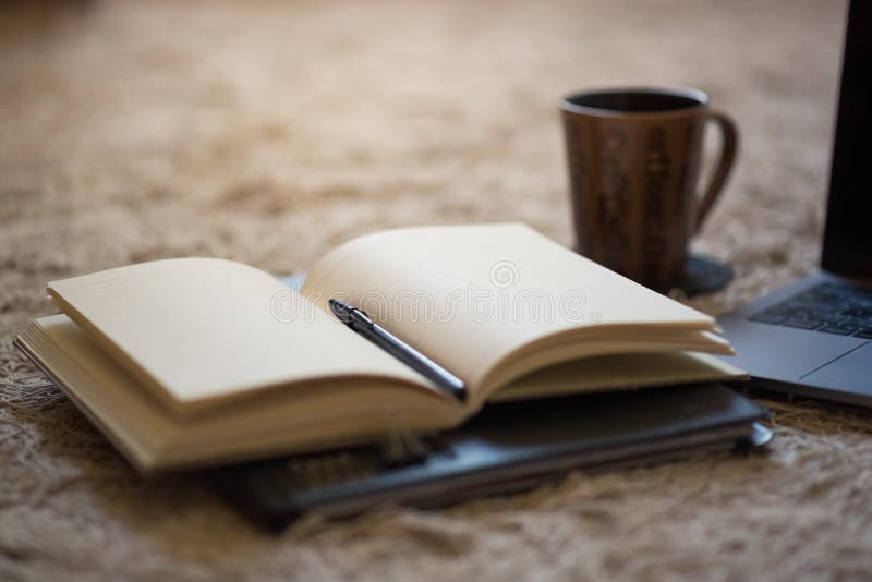 Un diario abierto con la pluma y las páginas en blanco illuminating ligeras calientes