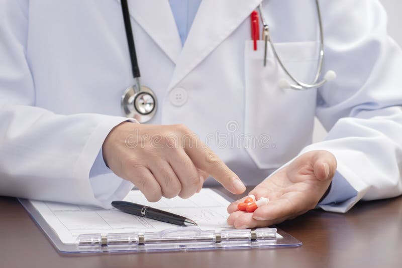 Un docteur masculin mettant le médicament sur la paume de la main et l'expliquant photo libre de droits Un docteur masculin mettant le médicament sur la paume de la main et l'expliquant photo libre de droits