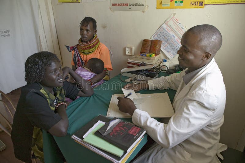 Un doctor consulta con la madre y los niños sobre HIV/AIDS en Pepo La Tumaini Jangwani, programa de rehabilitación de la comunida imagen de archivo Un doctor consulta con la madre y los niños sobre HIV/AIDS en Pepo La Tumaini Jangwani, programa de rehabilitación de la comunida imagen de archivo