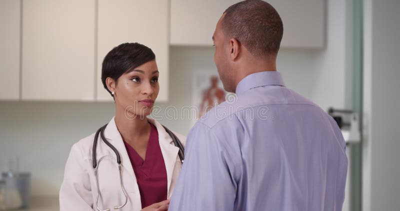 Un doctor negro aconseja a una paciente afroamericana en su oficina almacen de metraje de vídeo