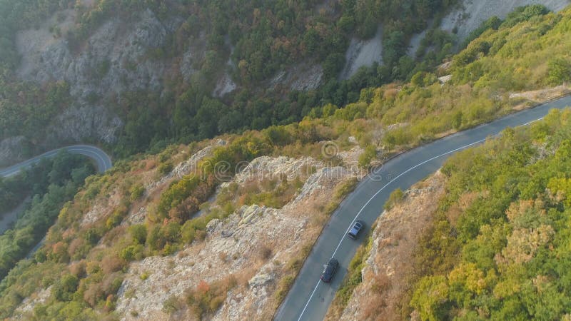 Un drone suit les voitures qui roulent sur une route rocheuse très fréquentée Circulation dense sur le col en été banque de vidéos