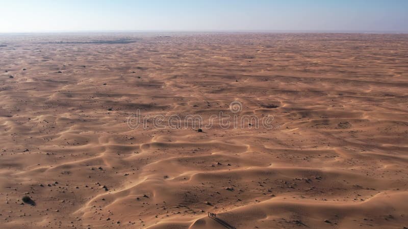 Un drone sur un groupe de touristes marchant le long de la dune de sable du désert. Dubaï une journée d'été ensoleillée banque de vidéos