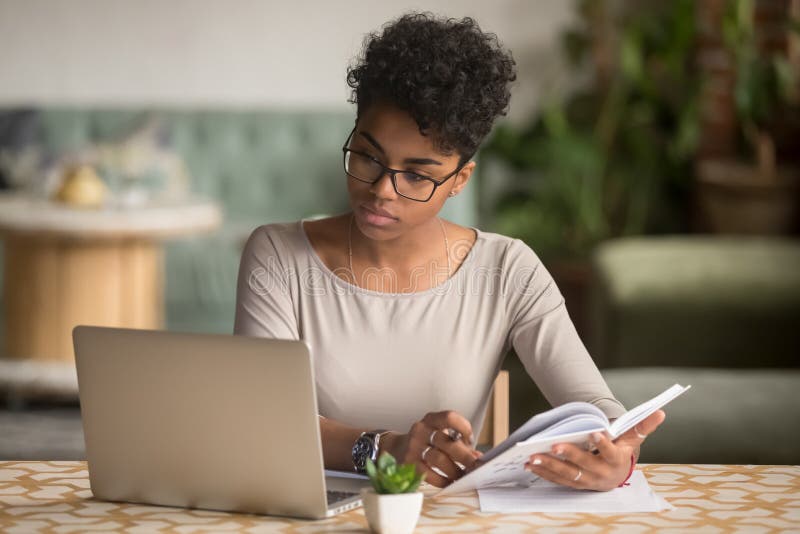 Un elev din Africa Orientată care se uită la un notebook de tip notebook care se ocupă de cercetare royalty free stock images