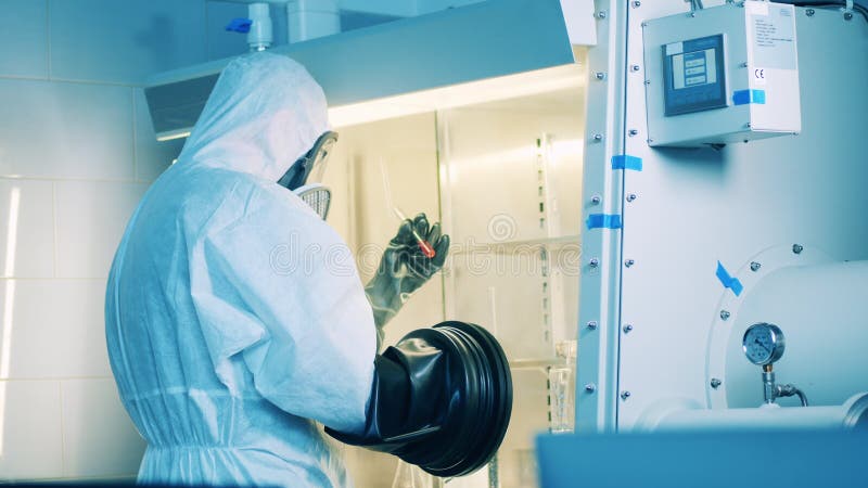 Un employé de laboratoire en combinaison hazmat utilise une armoire à vide pour la recherche