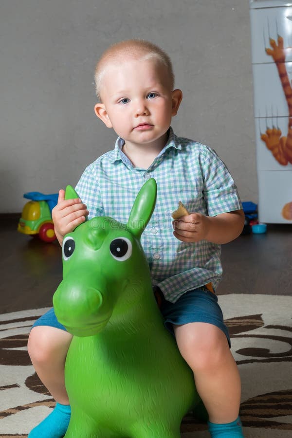 Un enfant saute sur un âne de jouet photo stock Un enfant saute sur un âne de jouet photo stock