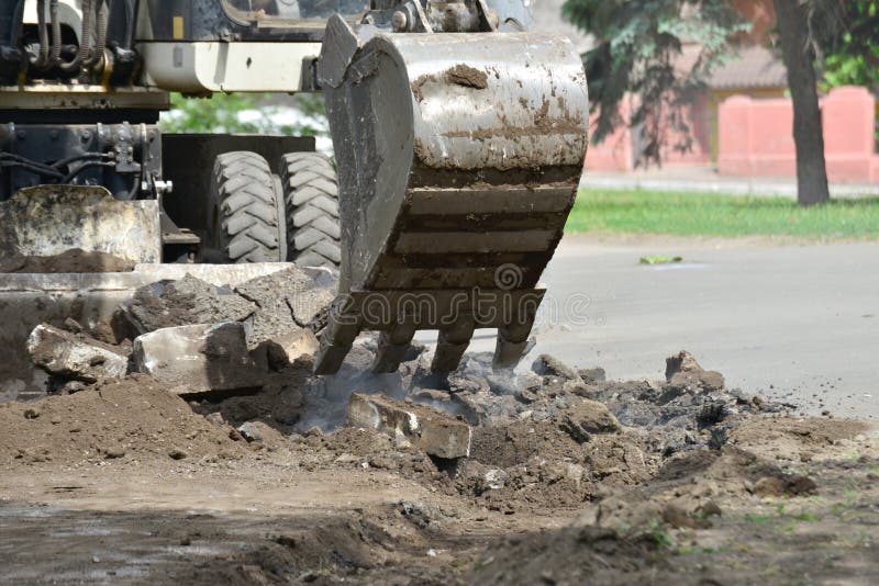 An excavator removes old asphalt for laying a new road. An excavator removes old asphalt for laying a new road.