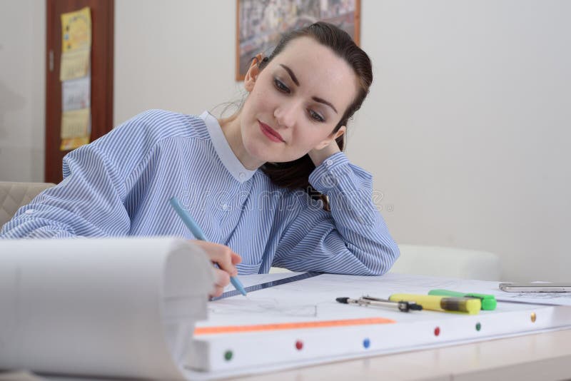 Un estudiante joven prepara el trabajo arquitectónico en una tabla con un papel y efectos de escritorio blancos de dibujo fotografía de archivo libre de regalías Un estudiante joven prepara el trabajo arquitectónico en una tabla con un papel y efectos de escritorio blancos de dibujo fotografía de archivo libre de regalías