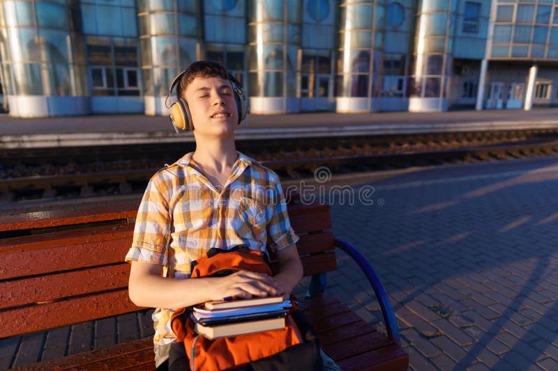 Un estudiante posa en una estación de tren un niño espera un tren en la plataforma leyendo libros y haciendo los deberes a fotos de archivo