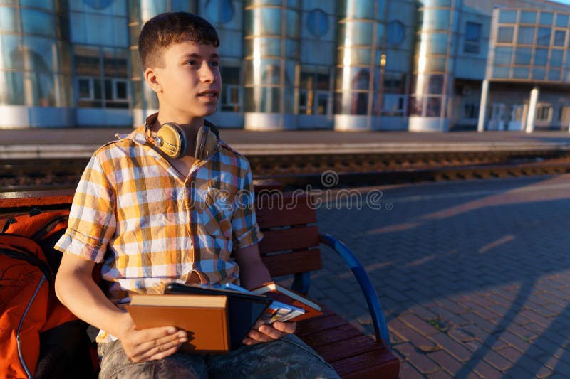 Un estudiante posa en una estación de tren un niño espera un tren en la plataforma leyendo libros y haciendo los deberes a fotografía de archivo