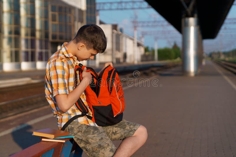 Un estudiante posa en una estación de tren un niño en la plataforma espera un tren que tiene una mochila y los libros van a estudi fotografía de archivo libre de regalías