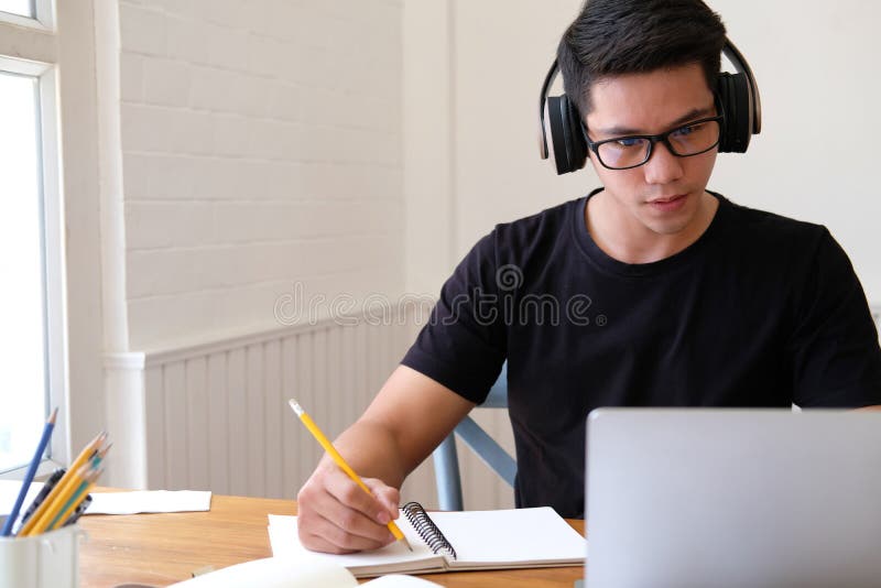Un estudiante universitario que estudia lecciones de aprendizaje con ordenador en lÃnea nota fotografía de archivo libre de regalías